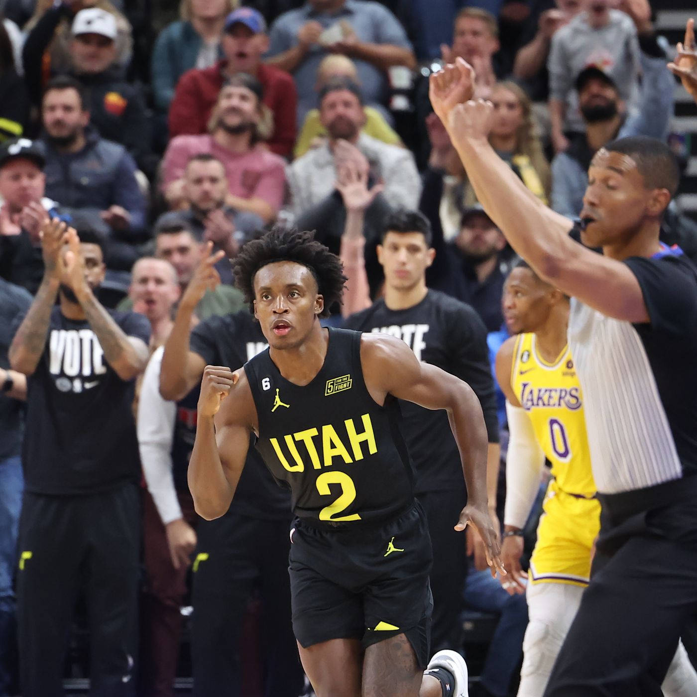 Utah 桌布 壁紙 — 一位猶他爵士隊籃球運動員身穿黑黃球衣，在觀眾吶喊聲中飛奔越過湖人隊防守球員，進行一場激烈的比賽。