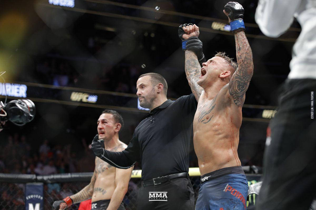 Victory 桌布 壁紙 — 一位獲勝的MMA拳手，手臂上有刺青，在燈光明亮的八角籠中，裁判宣布他獲勝時，他高舉拳頭慶祝勝利。