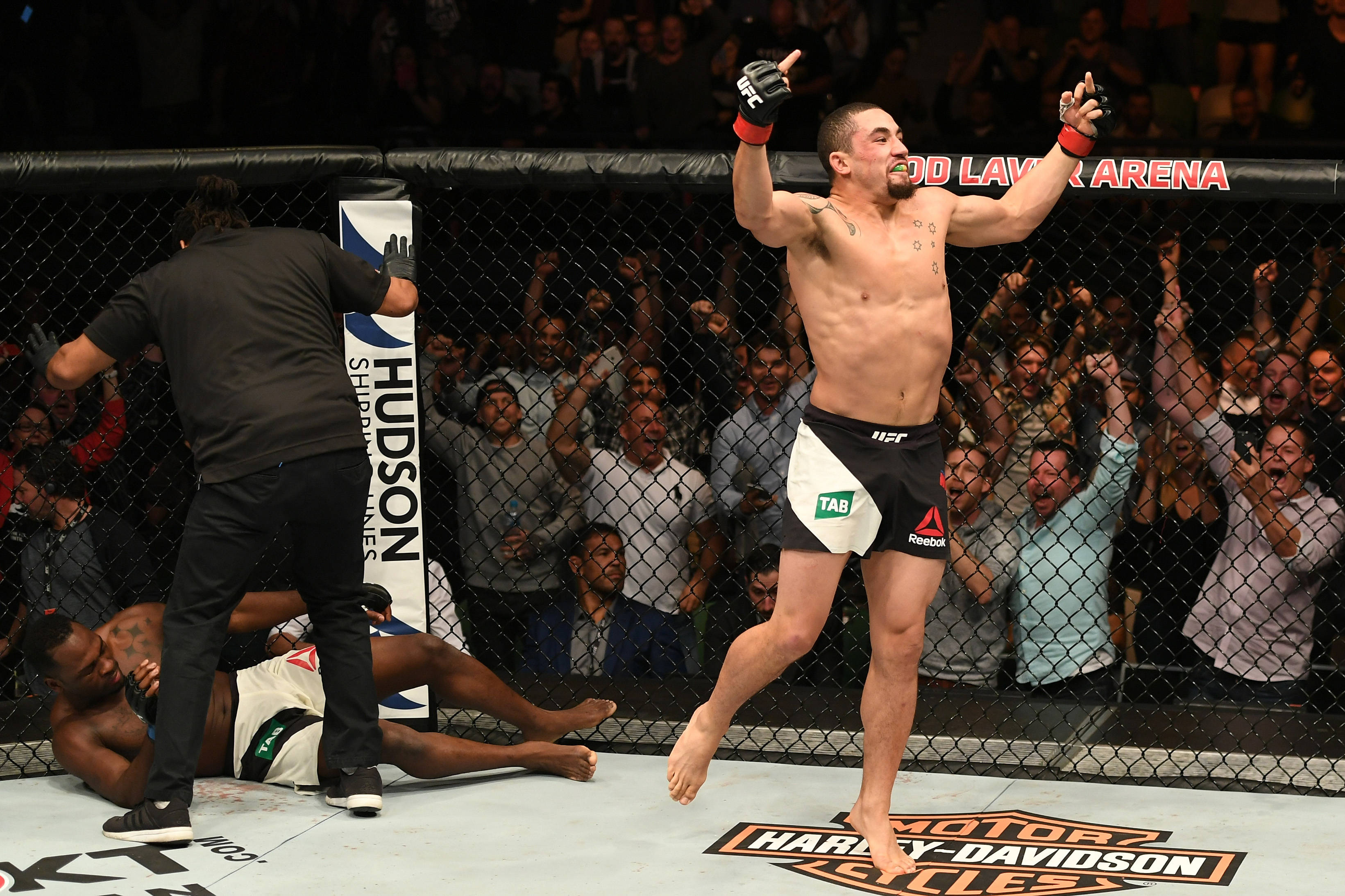 UFC 桌布 壁紙 — 一位獲勝的MMA拳手在八角籠中勝利慶祝，對手倒地敗北，觀眾瘋狂歡呼。