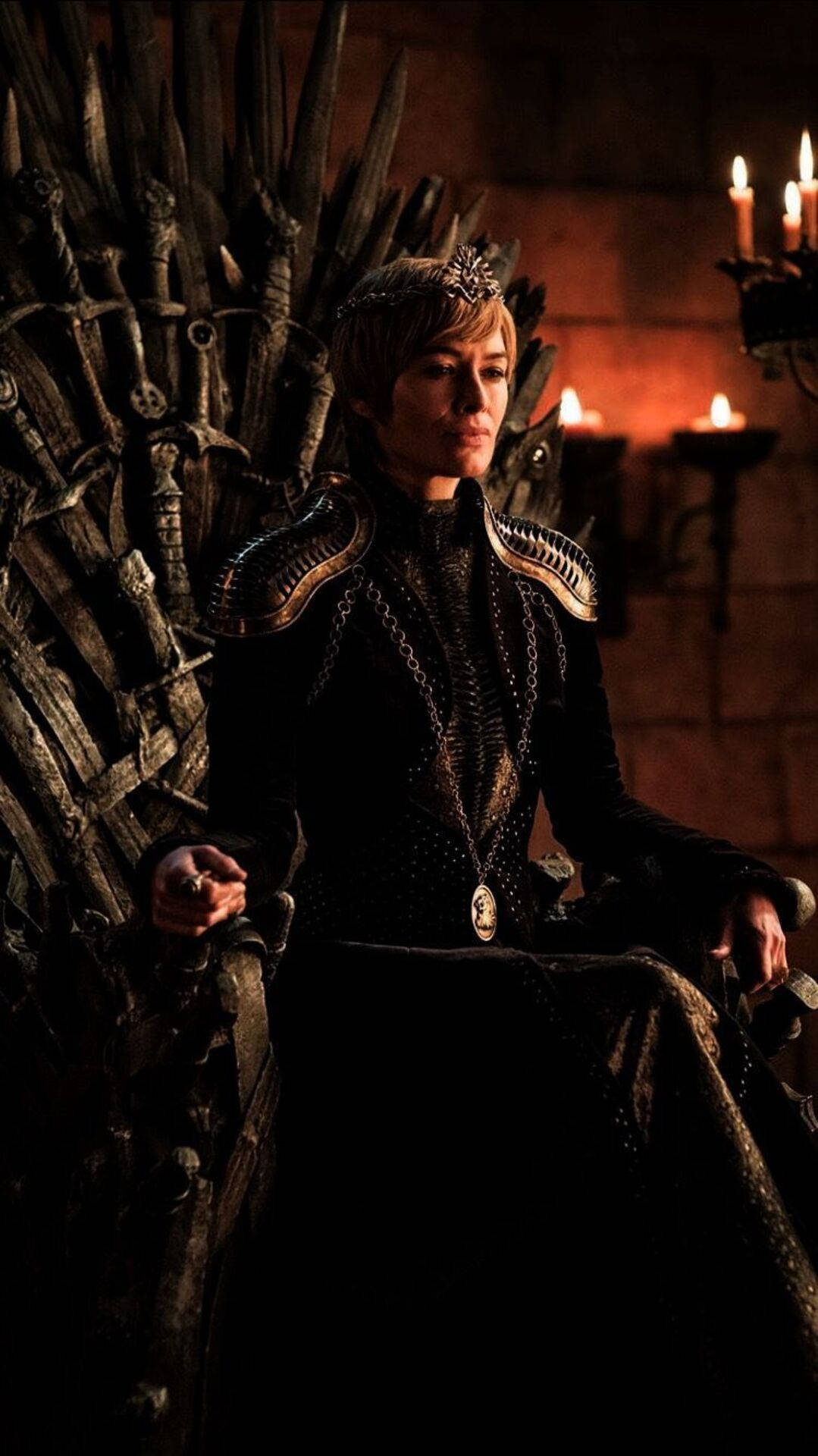 cersei lannister 桌布 壁紙 — 一位王者般的人物坐在劍之王座上，身處一個由搖曳燭光照亮的昏暗石室中。