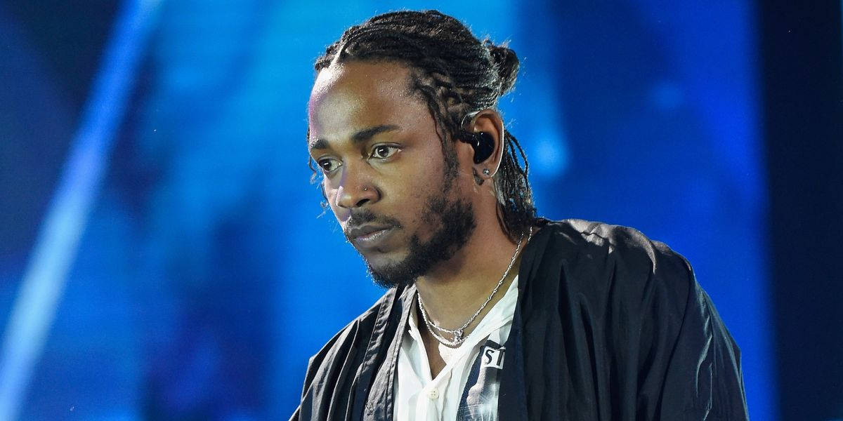 90s Rapper 桌布 壁紙 — 一位男性表演者，編織頭髮並戴著耳機，在充滿活力的藍色舞台背景下專注地凝視。