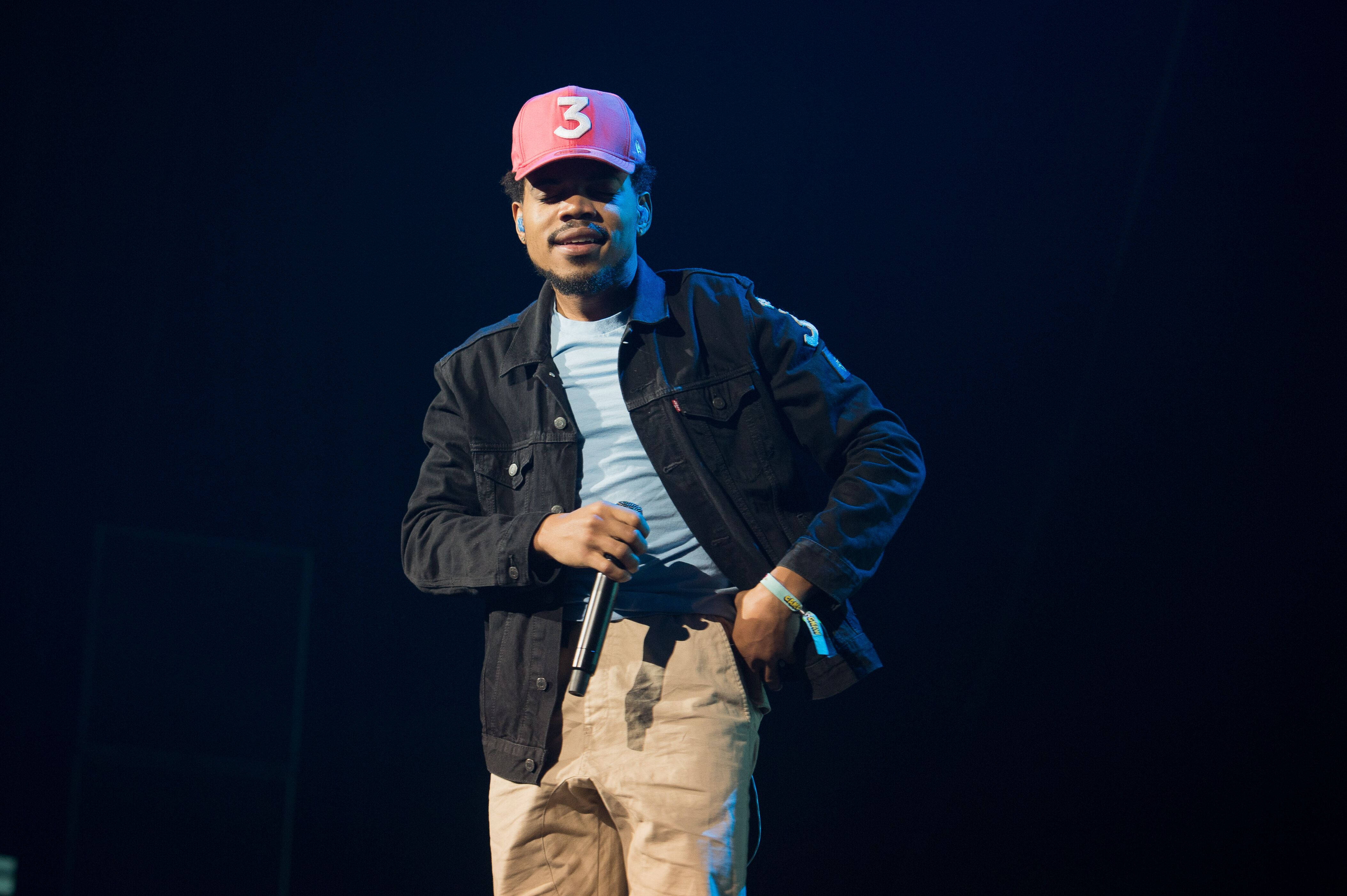 chance 桌布 壁紙 — 一位男性表演者戴著粉紅色帽子，上面有白色數字三，在黑暗的舞台燈光下對著麥克風唱歌。