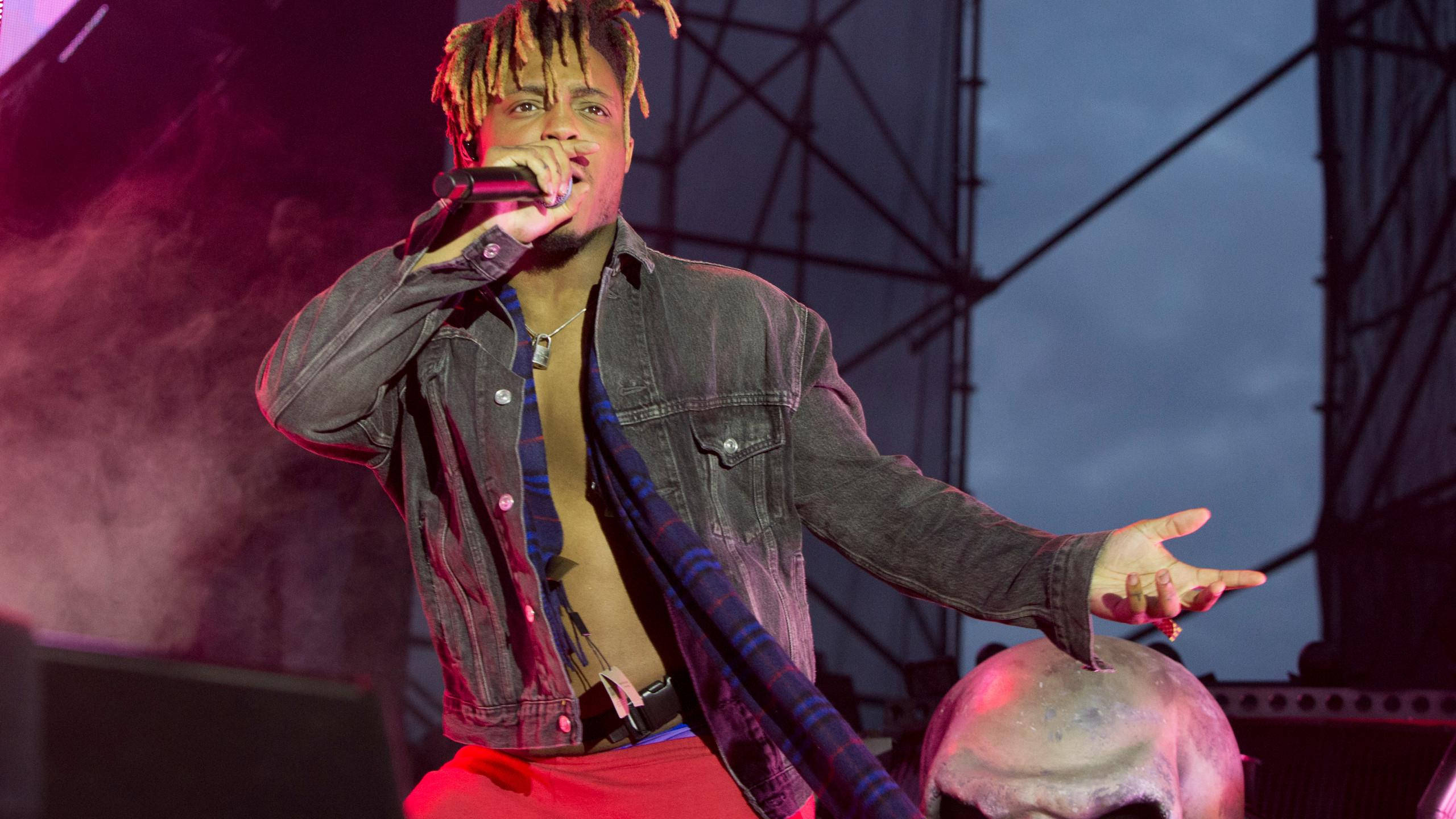 Juice Wrld Desktop 桌布 壁紙 — 一位男性饒舌歌手留著辮子，在紫色燈光下拿著麥克風表演，煙霧在他周圍旋轉。