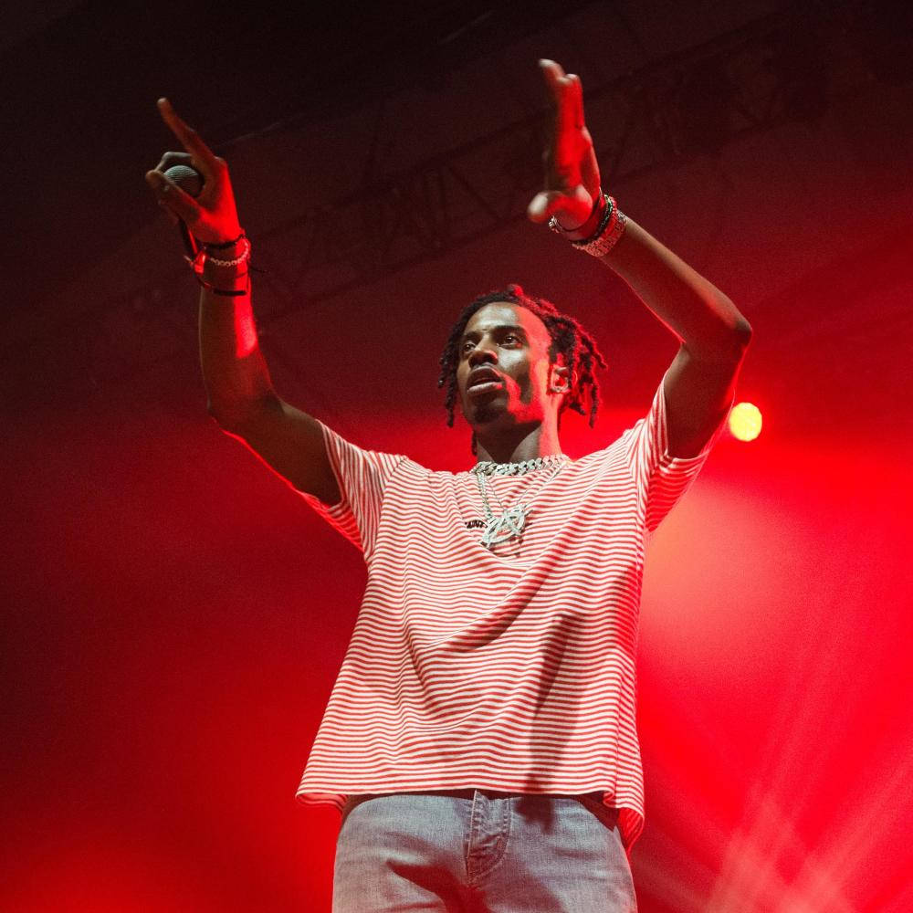Carti 桌布 壁紙 — 一位男饒舌歌手在強烈的紅色舞台燈光下，手持麥克風並向上做手勢，為群眾注入活力。