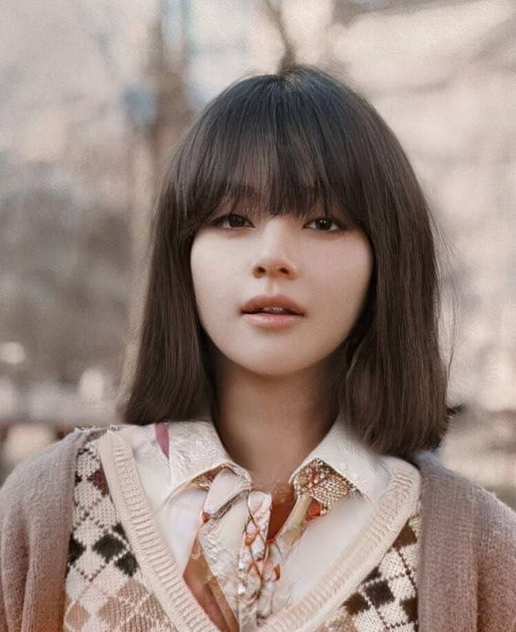 girls 桌布 壁紙 — 一位留著深色鮑伯頭和瀏海的年輕女性，穿著印花毛衣背心搭配花卉圖案襯衫，溫柔地凝視著。