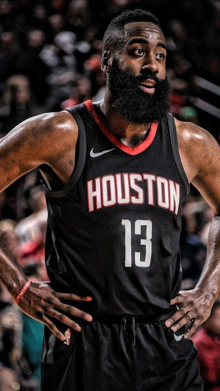 James Harden 桌布 壁紙 — 一位留著濃密鬍鬚、專注的籃球運動員，在明亮的場館燈光下比賽時，穿著黑色休士頓13號球衣。