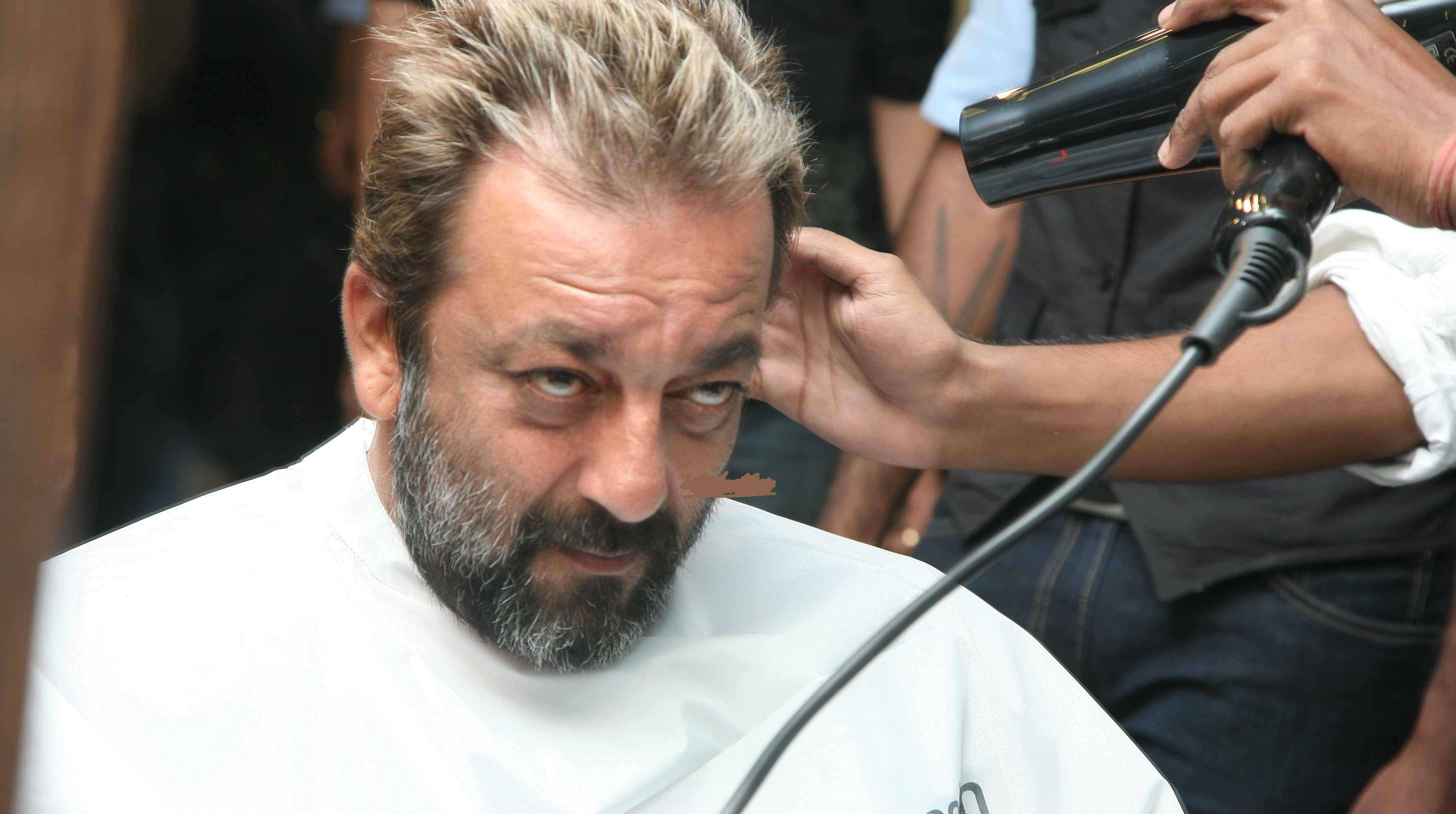 Sanjay 桌布 壁紙 — 一位留著灰白鬍子的男士坐在理髮椅上，造型師正用吹風機為他吹整頭髮。