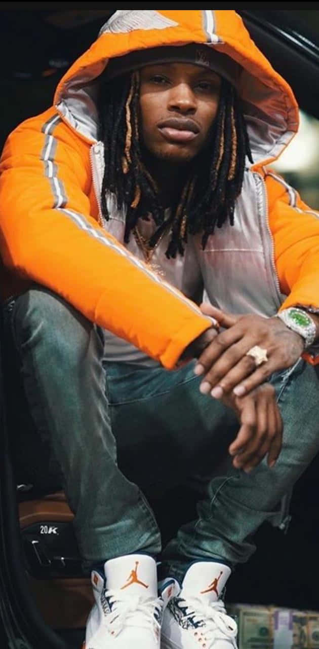 身穿橙色外套和Jordan運動鞋的男子坐在車裡，旁邊有錢 — King Von 壁紙