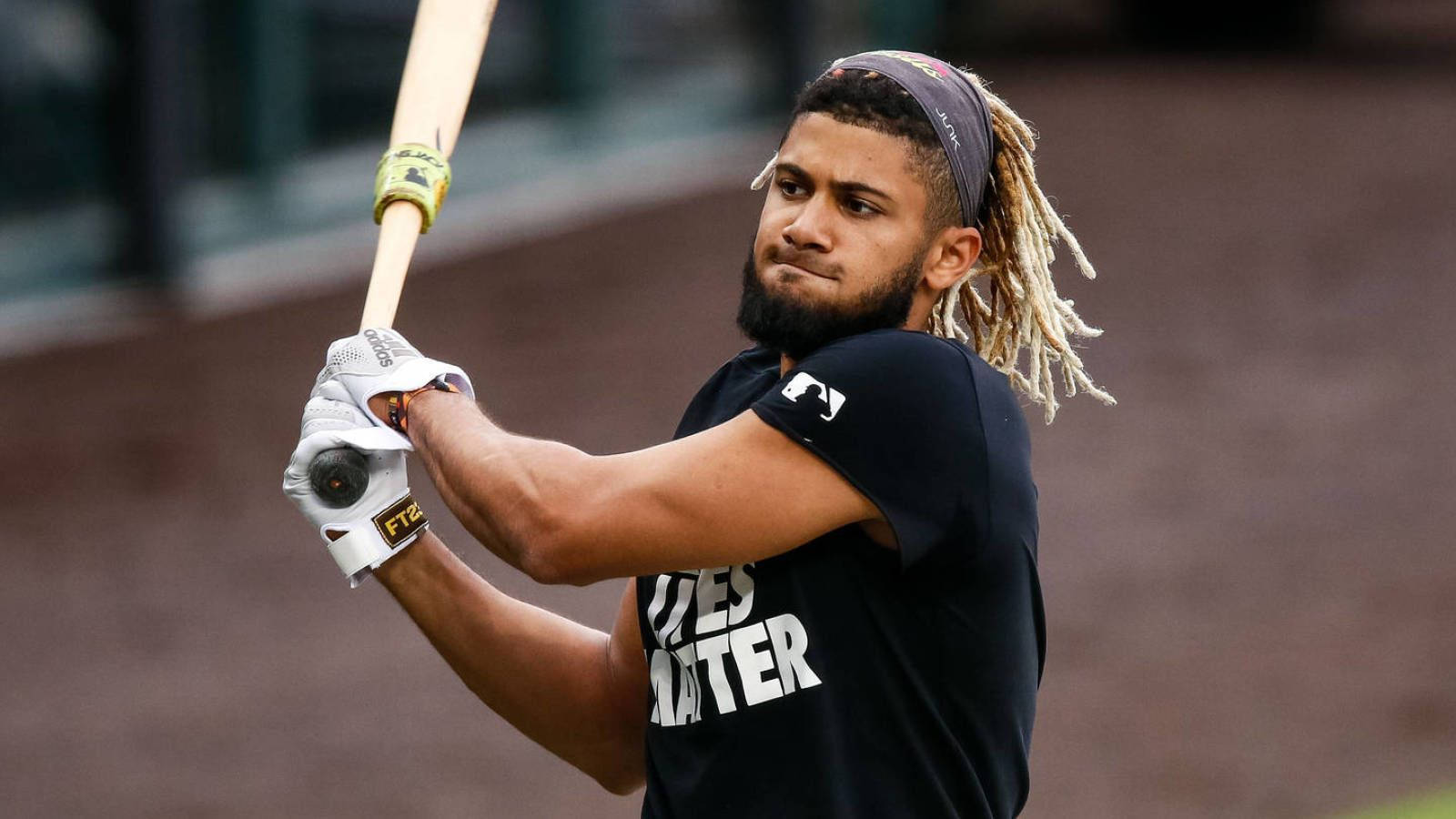 Tatis 桌布 壁紙 — 一位留著辮子頭、戴著頭帶的棒球運動員在練習中以專注的姿勢揮棒。