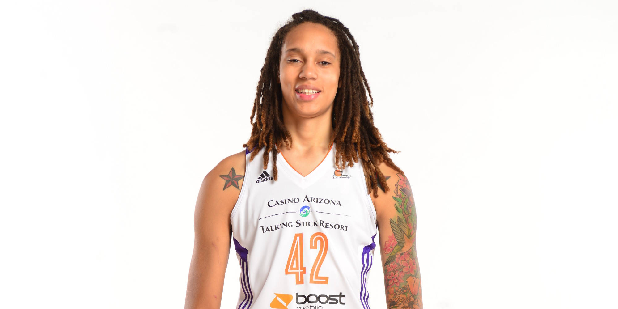 Brittney 桌布 壁紙 — 一位留著辮子頭、有刺青的女籃球員，身穿白色42號球衣，在純白背景前微笑。