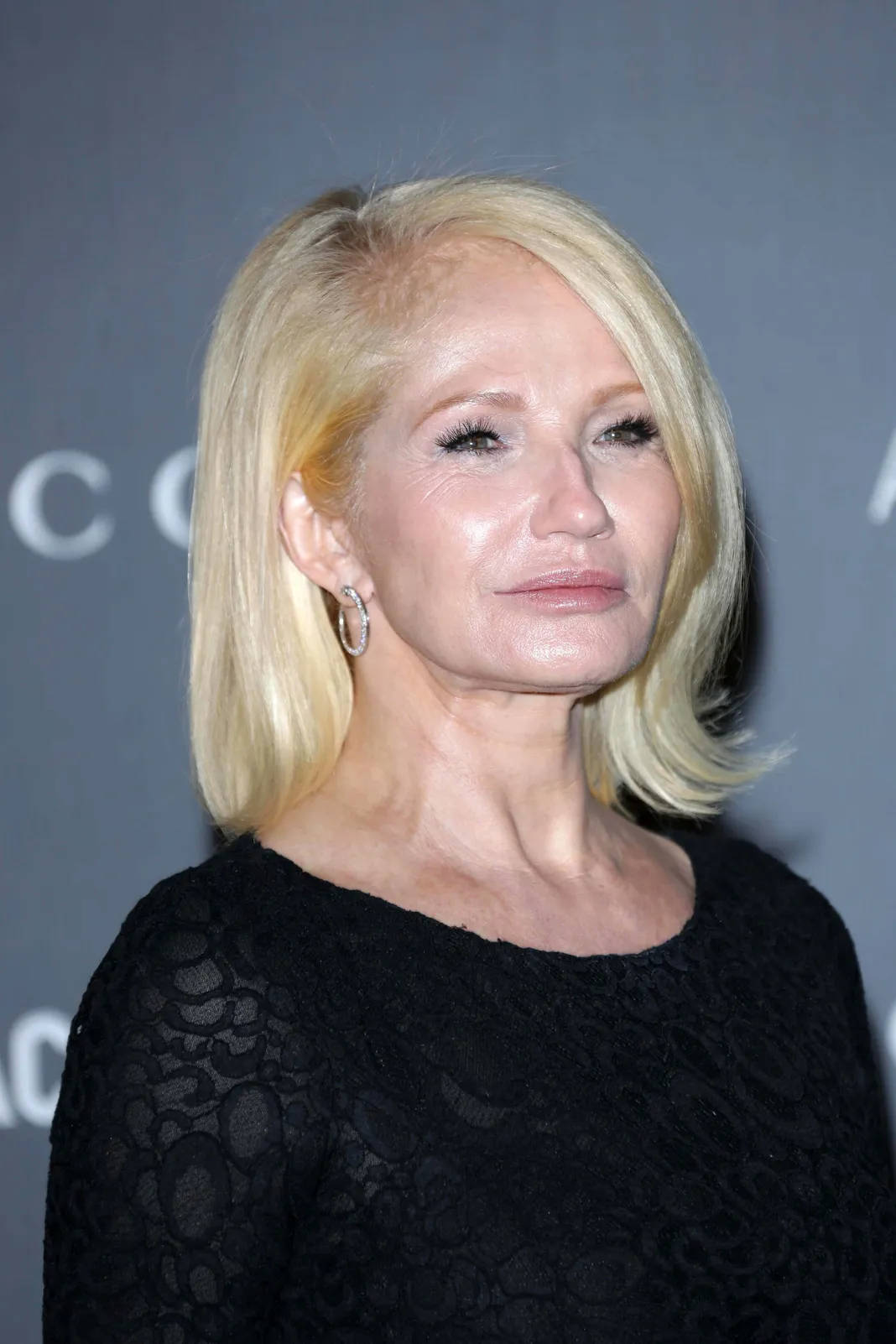 Celebrity 桌布 壁紙 — 一位留著金色鮑伯頭、戴著銀色圓環耳環的女性，在灰色品牌背景前穿著黑色蕾絲上衣。