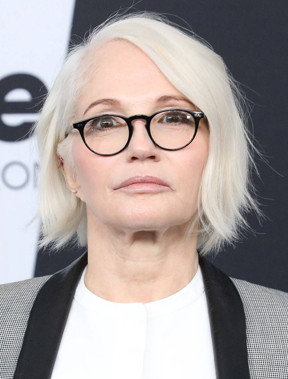 Celebrity 桌布 壁紙 — 一位留著鉑金色鮑伯頭、戴著黑框眼鏡、身穿格紋西裝外套的女子的特寫肖像。