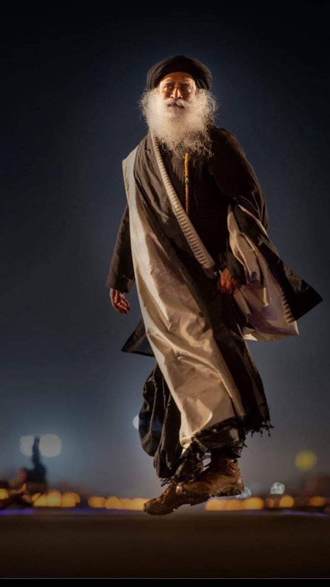 Sadhguru 桌布 壁紙 — 一位留著長長白鬍子、戴著黑色頭巾的長者，在漆黑的夜空下看似懸浮在半空中，下方是模糊的城市燈光。