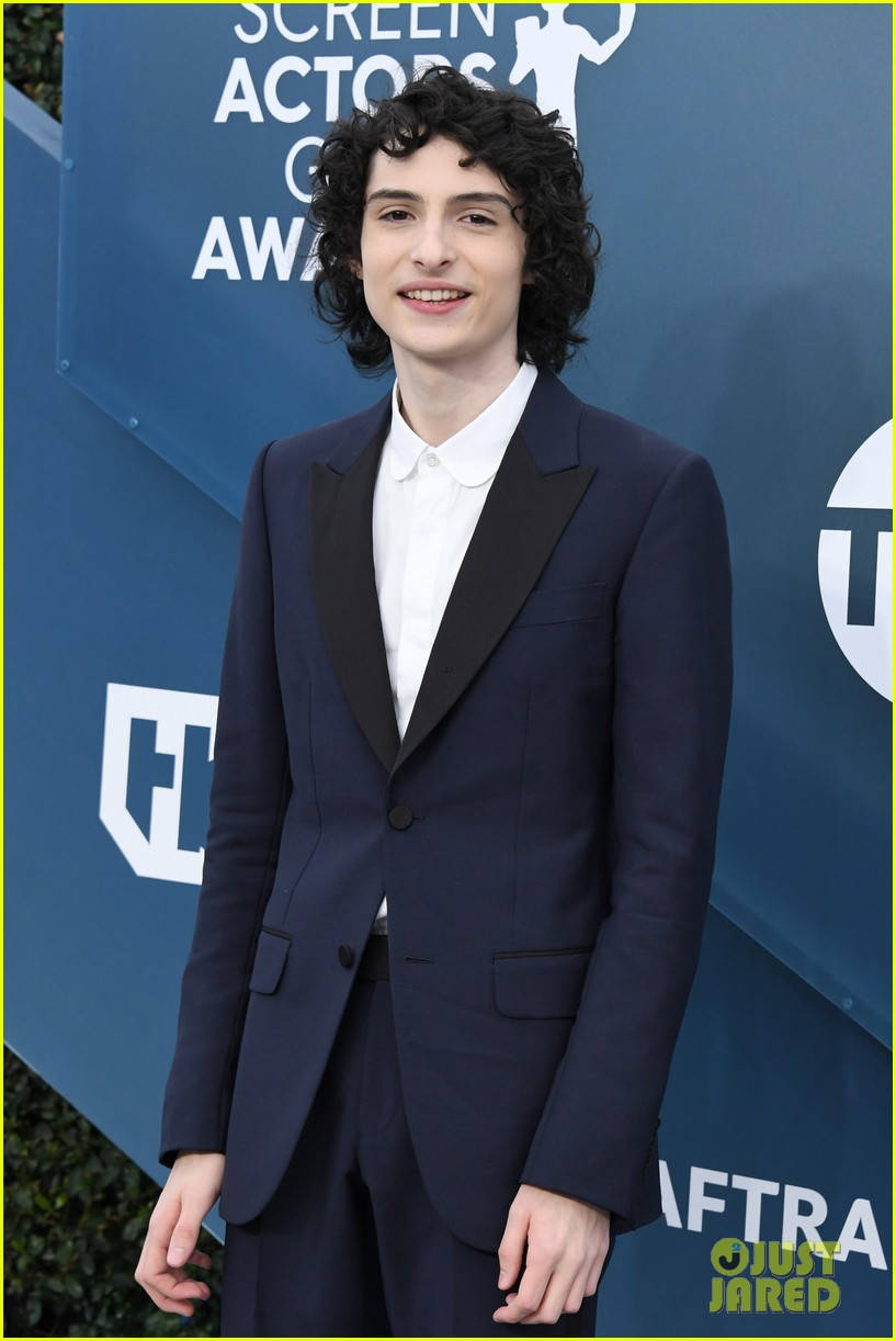 Celebrity 桌布 壁紙 — 一位留著黑色捲髮的年輕男子，身穿海軍藍色燕尾服搭配黑色領子，在藍色Screen Actors Guild Awards背景前微笑。