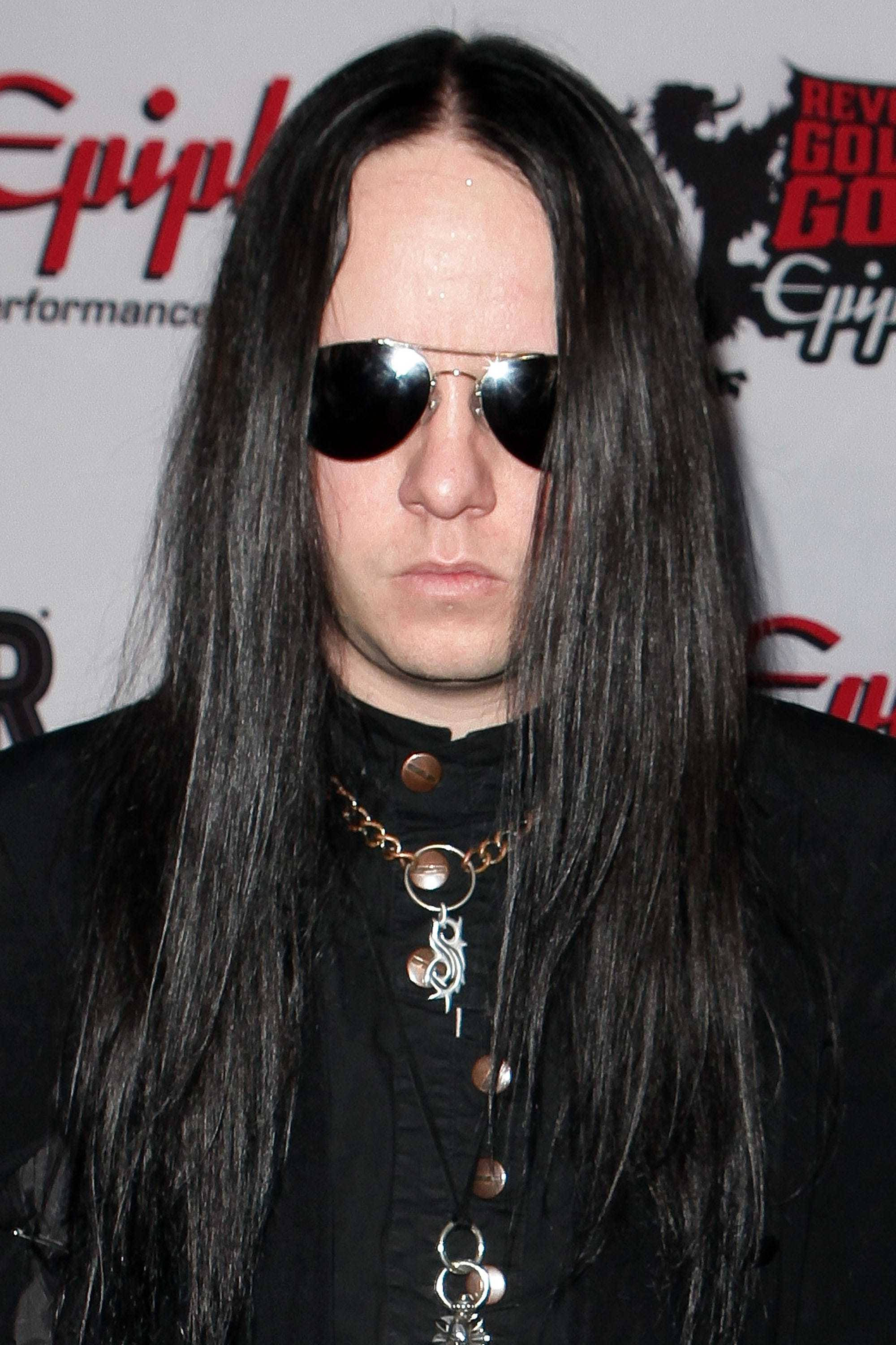 Joey Jordison 桌布 壁紙 — 一位留著黑色長髮、戴著飛行員太陽眼鏡的男子，在紅地毯活動中穿著黑色服裝，搭配多層金屬項鍊。