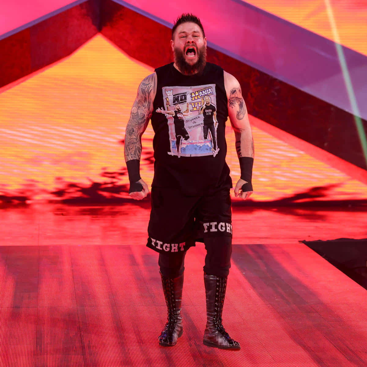 WWE 桌布 壁紙 — 一位留鬍子、有刺青的摔角手在紅色燈光的舞台上，在充滿活力的橙色和紫色燈光下咆哮。