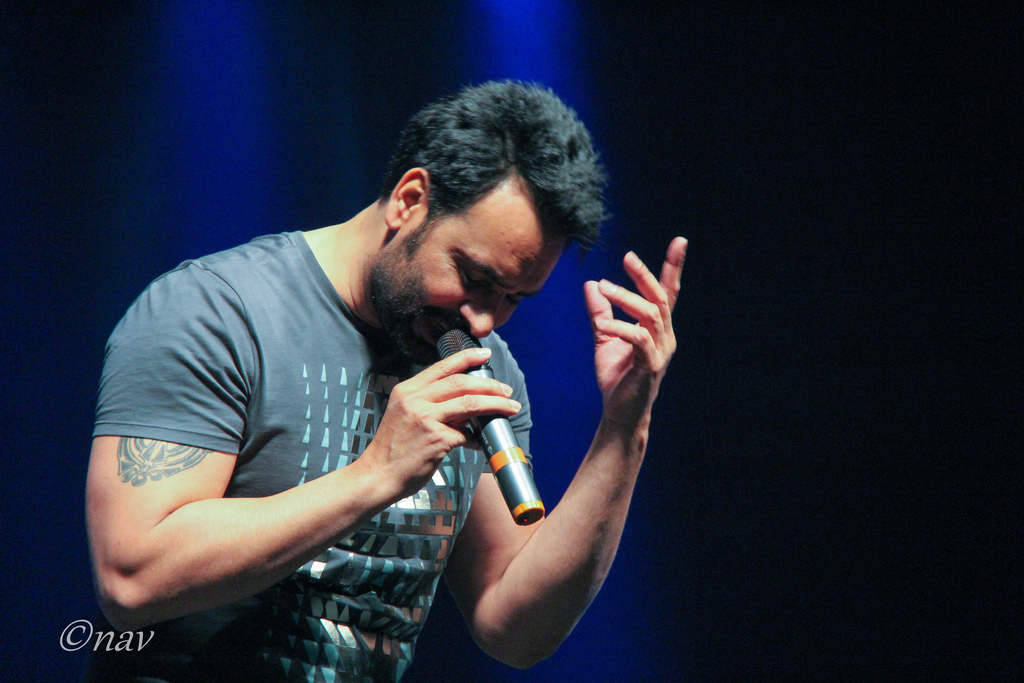 Babbu Maan 桌布 壁紙 — 一位留鬍子、有刺青的男士在藍色舞台燈光下熱情地對著麥克風唱歌。