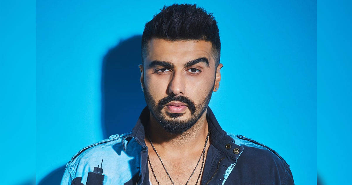 Arjun Kapoor 桌布 壁紙 — 一位留鬍子、頭髮造型時尚的男子，在充滿活力的藍色攝影棚背景和戲劇性燈光下，凝視著鏡頭。