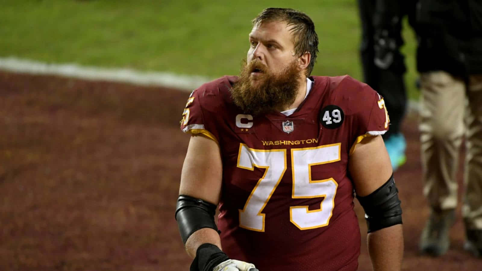 留鬍子的NFL球員在夜間足球場上穿著酒紅色華盛頓球衣號碼75。 — 傑克遜維爾美洲虎 GIF 壁紙