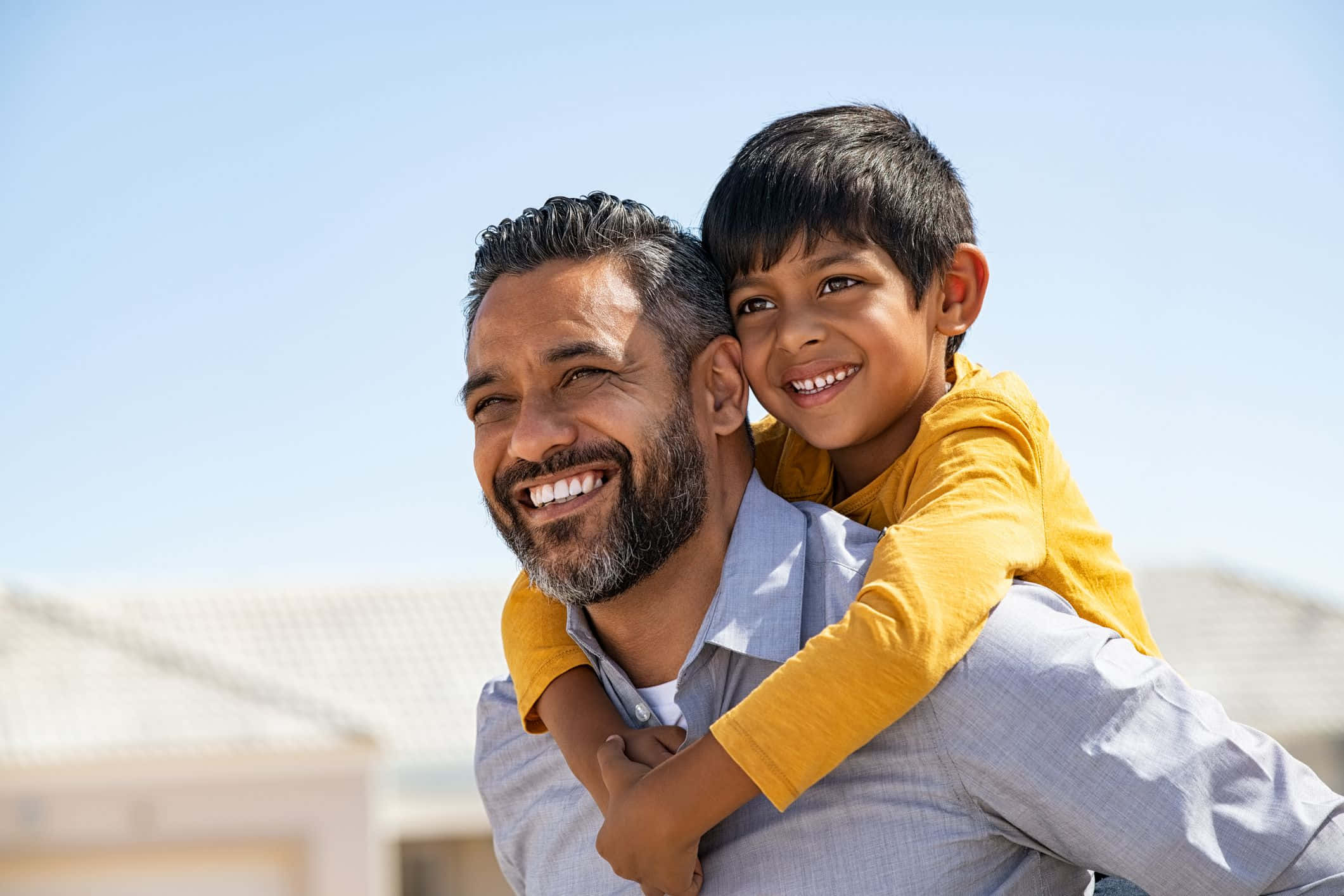 Father And Son 桌布 壁紙 — 一位留鬍子的快樂父親在晴朗的藍天下將微笑的兒子扛在肩上。