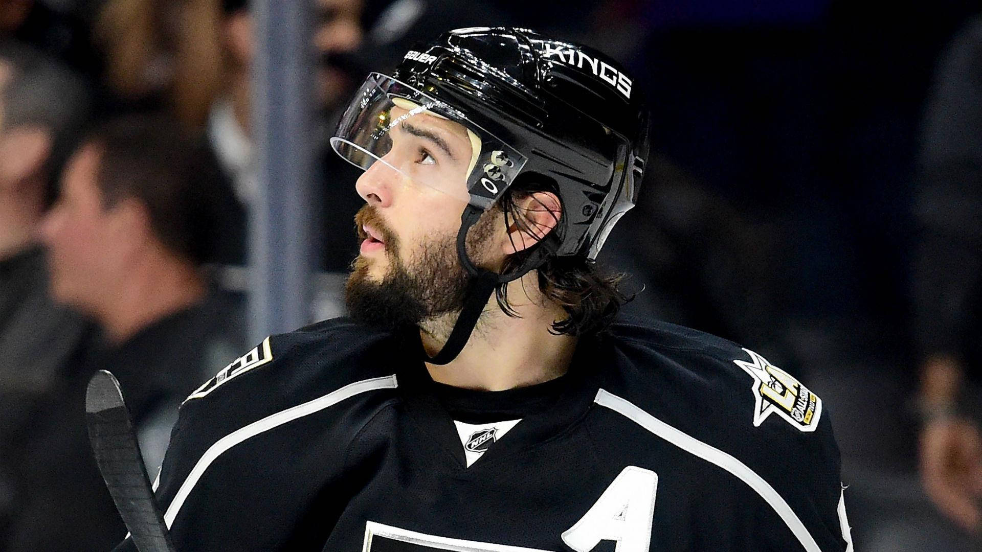 hockey 桌布 壁紙 — 一位留鬍子的曲棍球運動員身穿黑色Kings球衣，在比賽中專注地向上看的特寫。