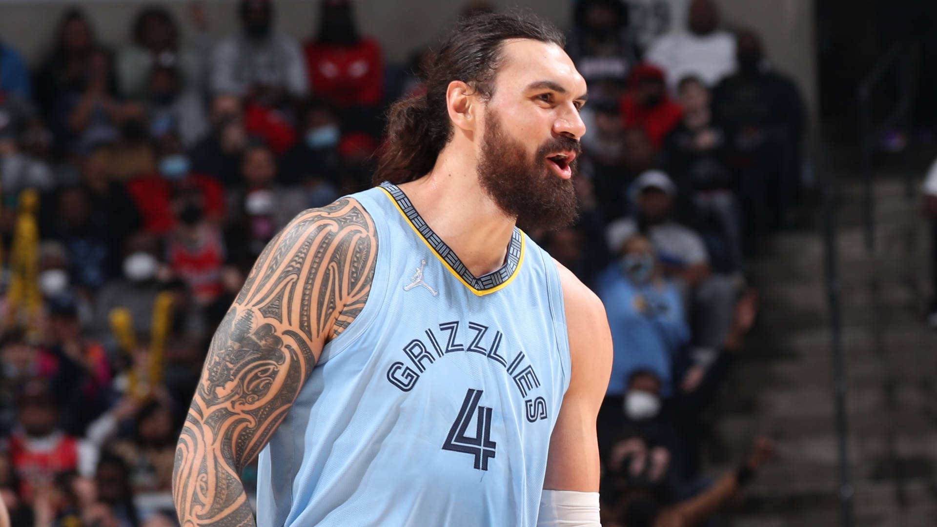 Steven Adams 桌布 壁紙 — 一位留鬍子的籃球運動員，身穿淺藍色灰熊隊球衣，背號4號，手臂上有部落紋身，在比賽中專注地站立。