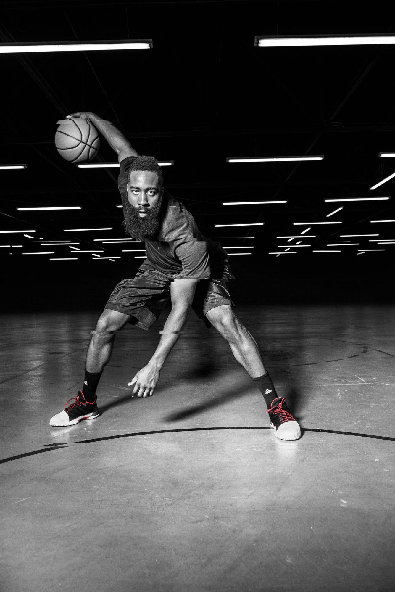 James Harden 桌布 壁紙 — 一位留鬍子的籃球運動員以黑白風格蹲低，在明亮的頭頂燈光下持球。