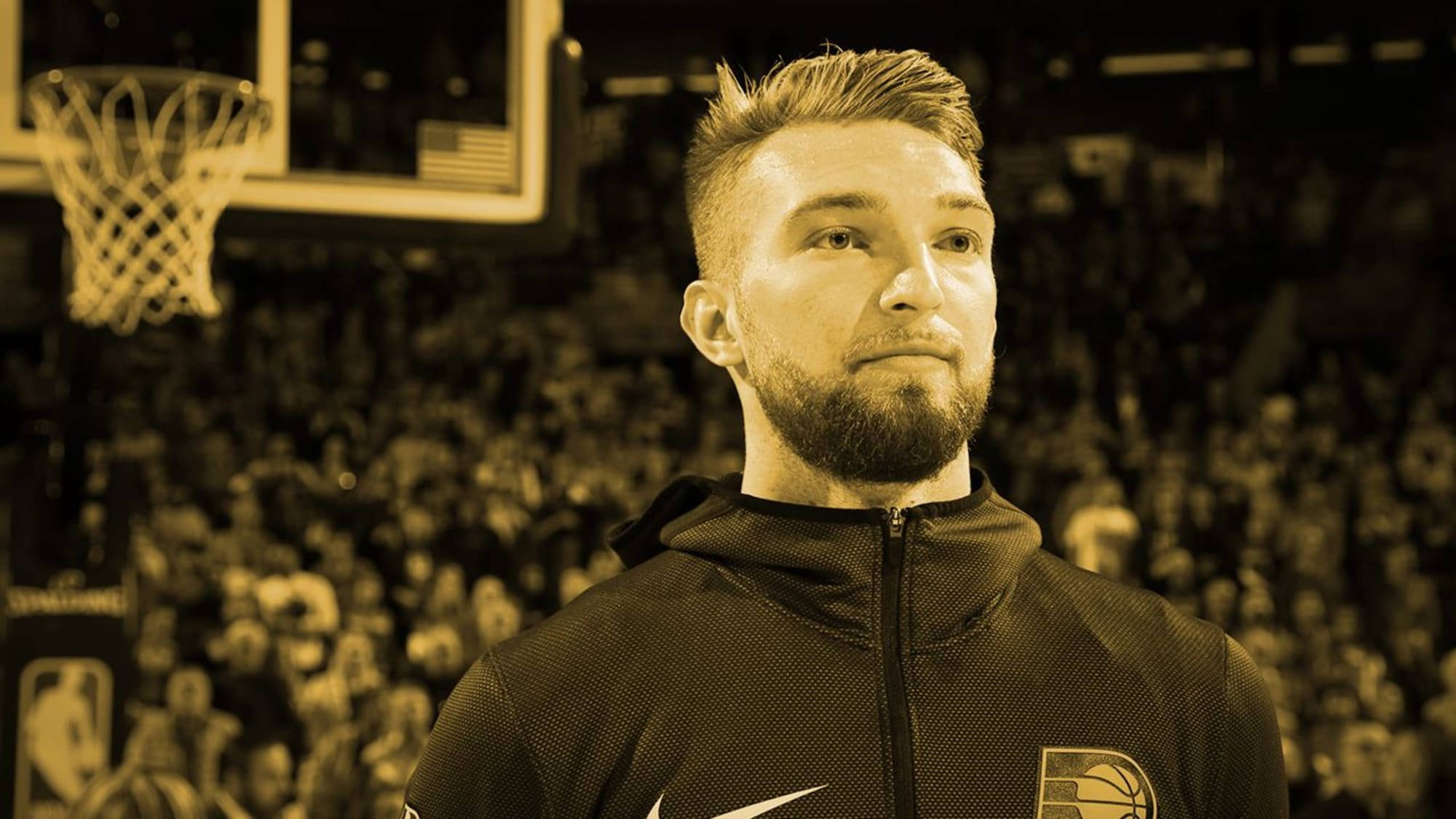domantas sabonis 桌布 壁紙 — 一位留鬍子的籃球運動員在棕褐色調的球場上沉思地凝視，身後有籃框和人群。