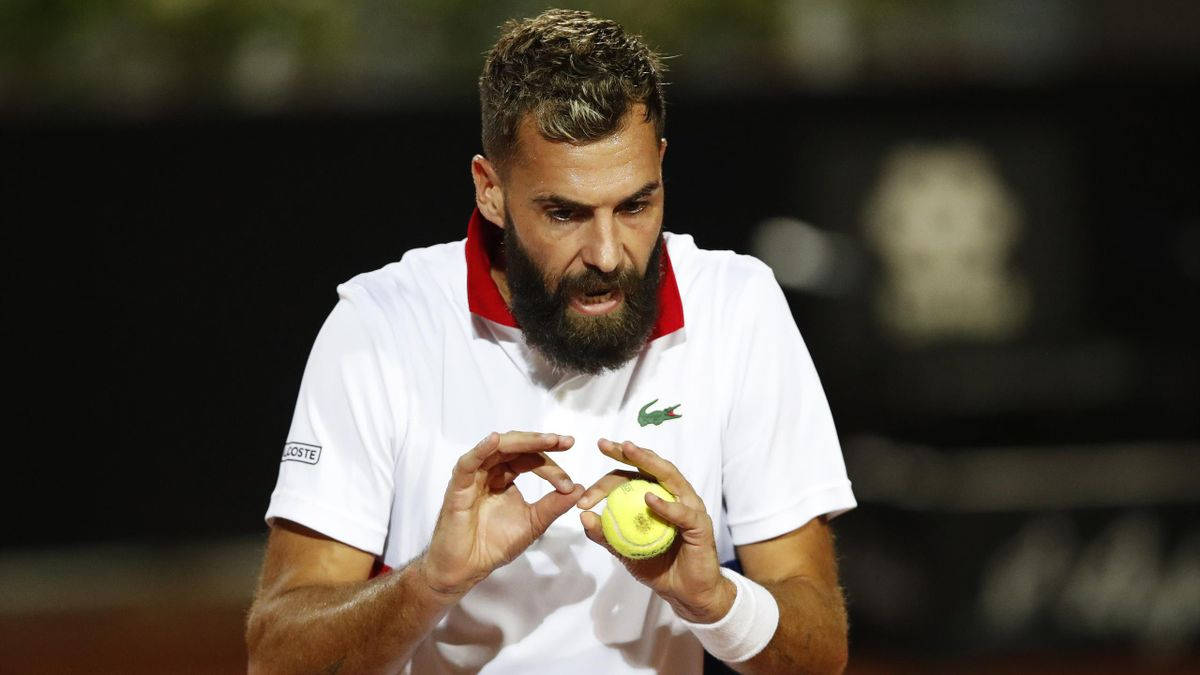 Tennis 桌布 壁紙 — 一位留鬍子的網球運動員在體育館燈光下專注於手中的黃色網球。