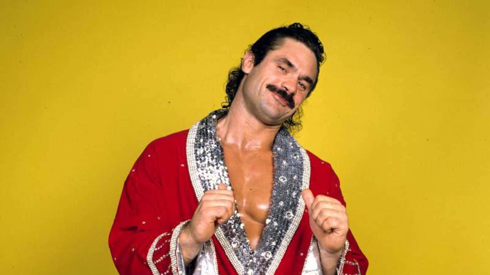 Wrestling 桌布 壁紙 — 一位留鬍子的肌肉摔角手，在亮黃色背景前穿著紅色閃亮長袍。