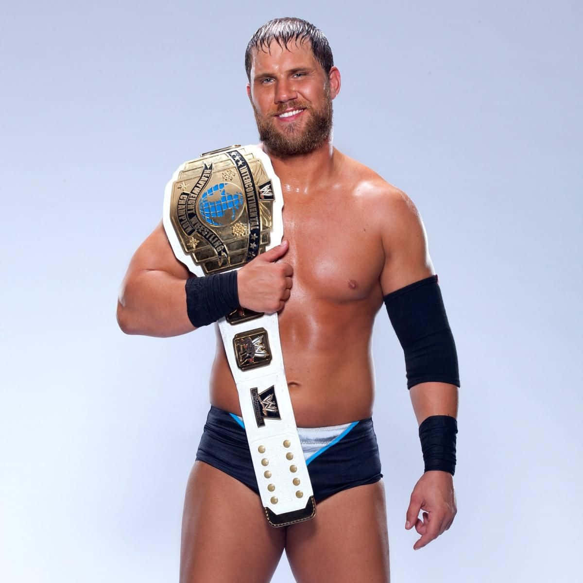 WWE 桌布 壁紙 — 一位留鬍子的肌肉摔角手，在純淺藍色背景前自豪地舉起一條金白色的冠軍腰帶。