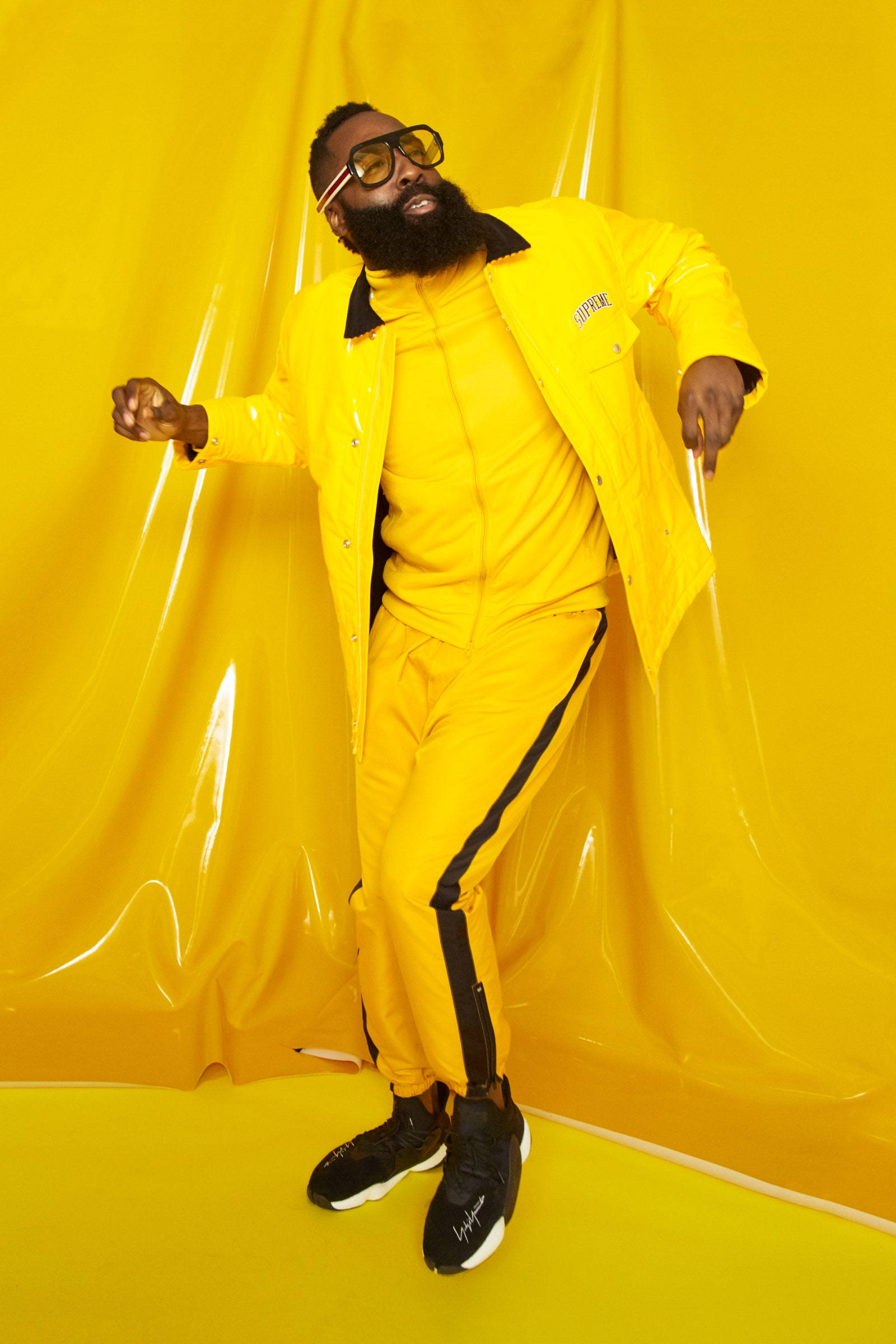 James Harden 桌布 壁紙 — 一位留鬍鬚、戴超大眼鏡的男子，身穿鮮黃色運動服，在相配的黃色背景前擺姿勢。