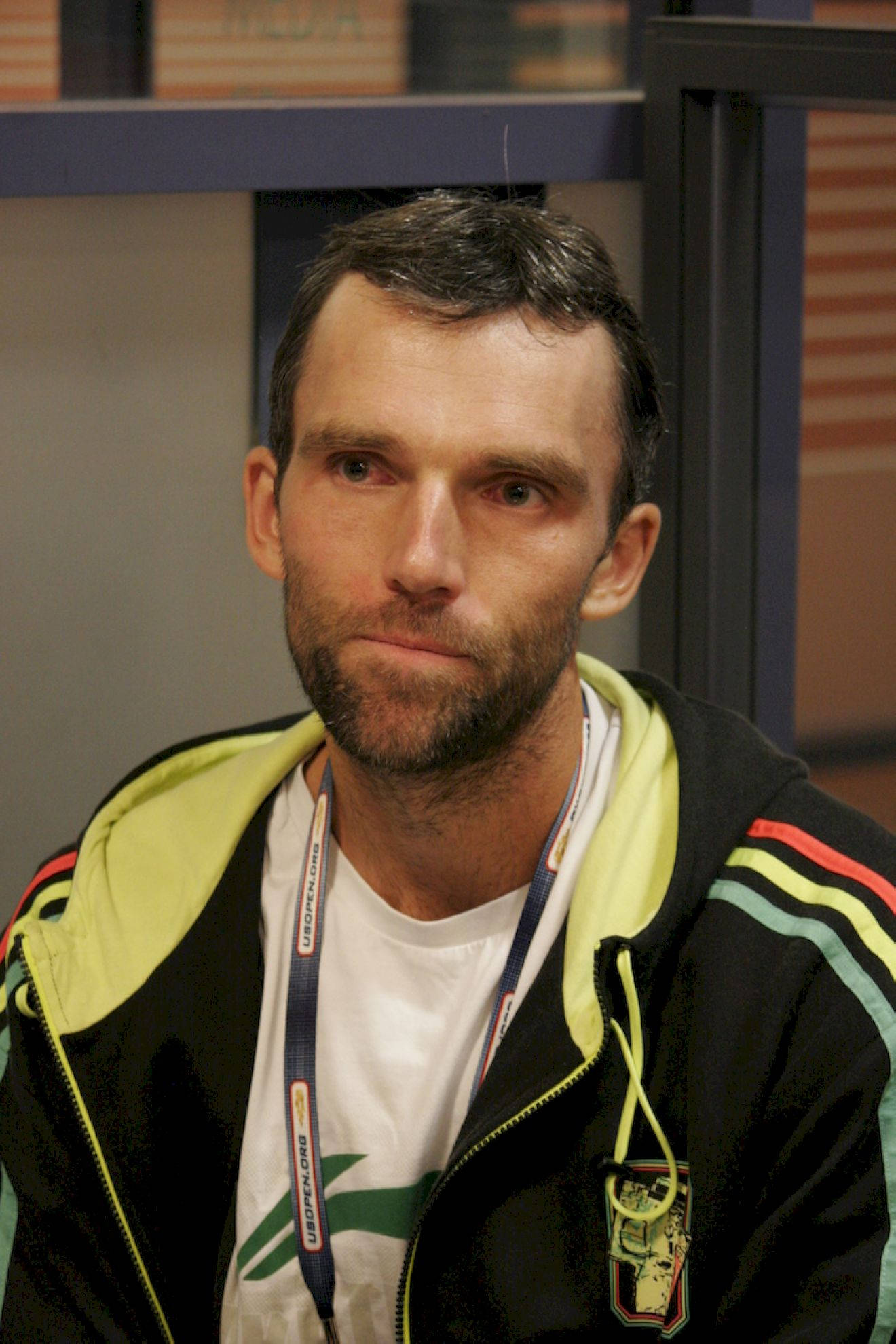 Tennis 桌布 壁紙 — 一位留鬍鬚、眼神銳利的男士，在室內柔和燈光下穿著色彩繽紛的運動外套。