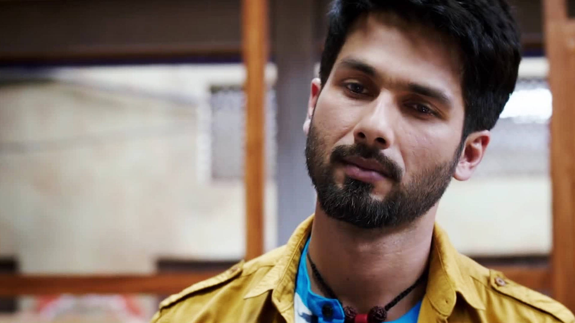 Shahid Kapoor 桌布 壁紙 — 一位留鬍鬚、眼神銳利的男士在室內穿著黃色外套，內搭藍色襯衫。