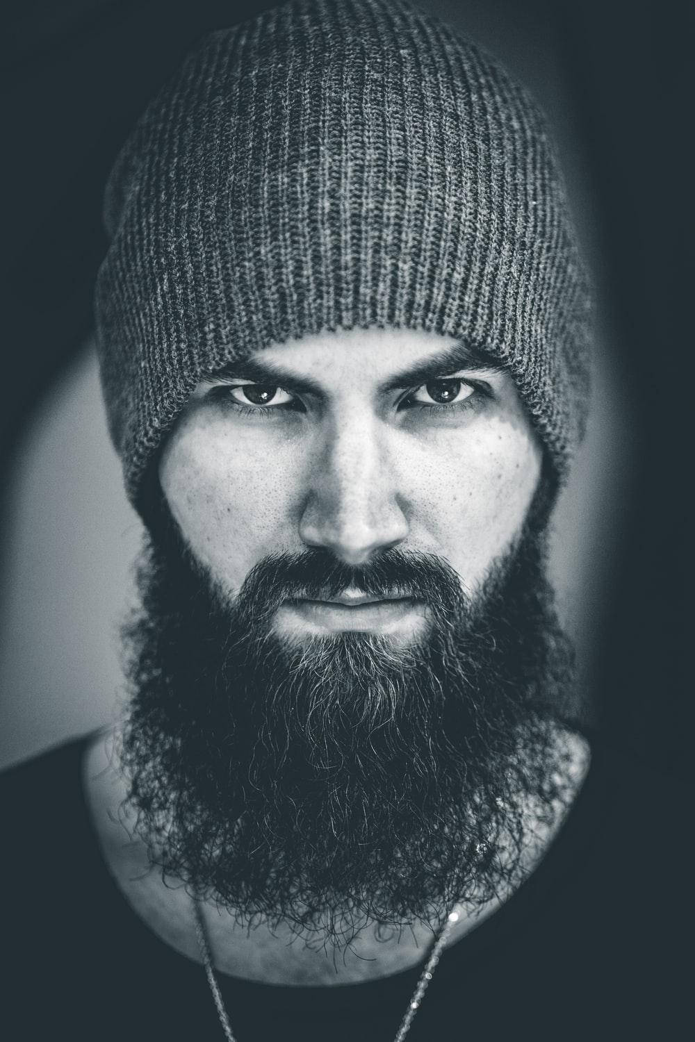 beard 桌布 壁紙 — 一位留鬍鬚、眼神銳利的男士戴著針織毛帽的黑白肖像。