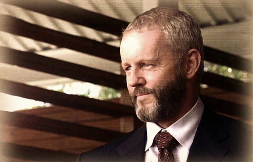 actor 桌布 壁紙 — 一位留鬍鬚、身穿西裝的男子在木條陰影下若有所思地望向一旁。