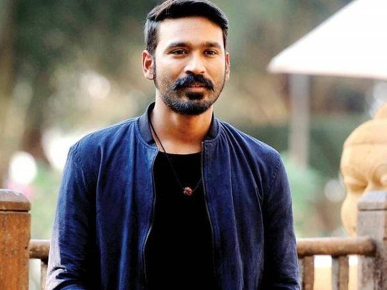 Dhanush 桌布 壁紙 — 一位留鬍鬚和鬍子的男士，身穿黑色襯衫外搭海軍藍外套，站在戶外木欄杆附近。