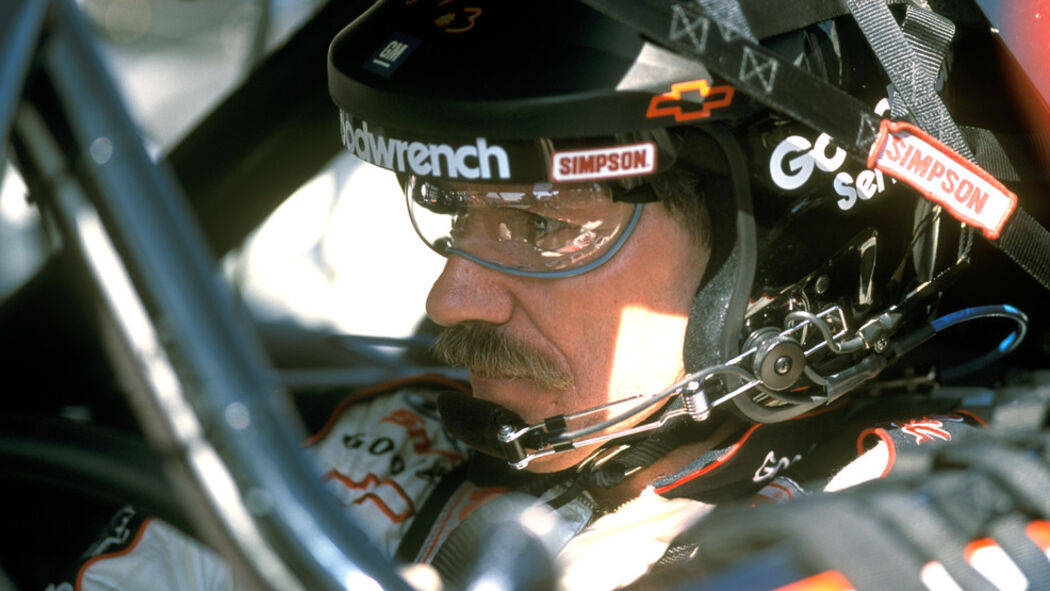 Dale Earnhardt 桌布 壁紙 — 一位留鬍鬚的專注賽車手，在賽車駕駛艙內戴著黑色Simpson頭盔和護目鏡。