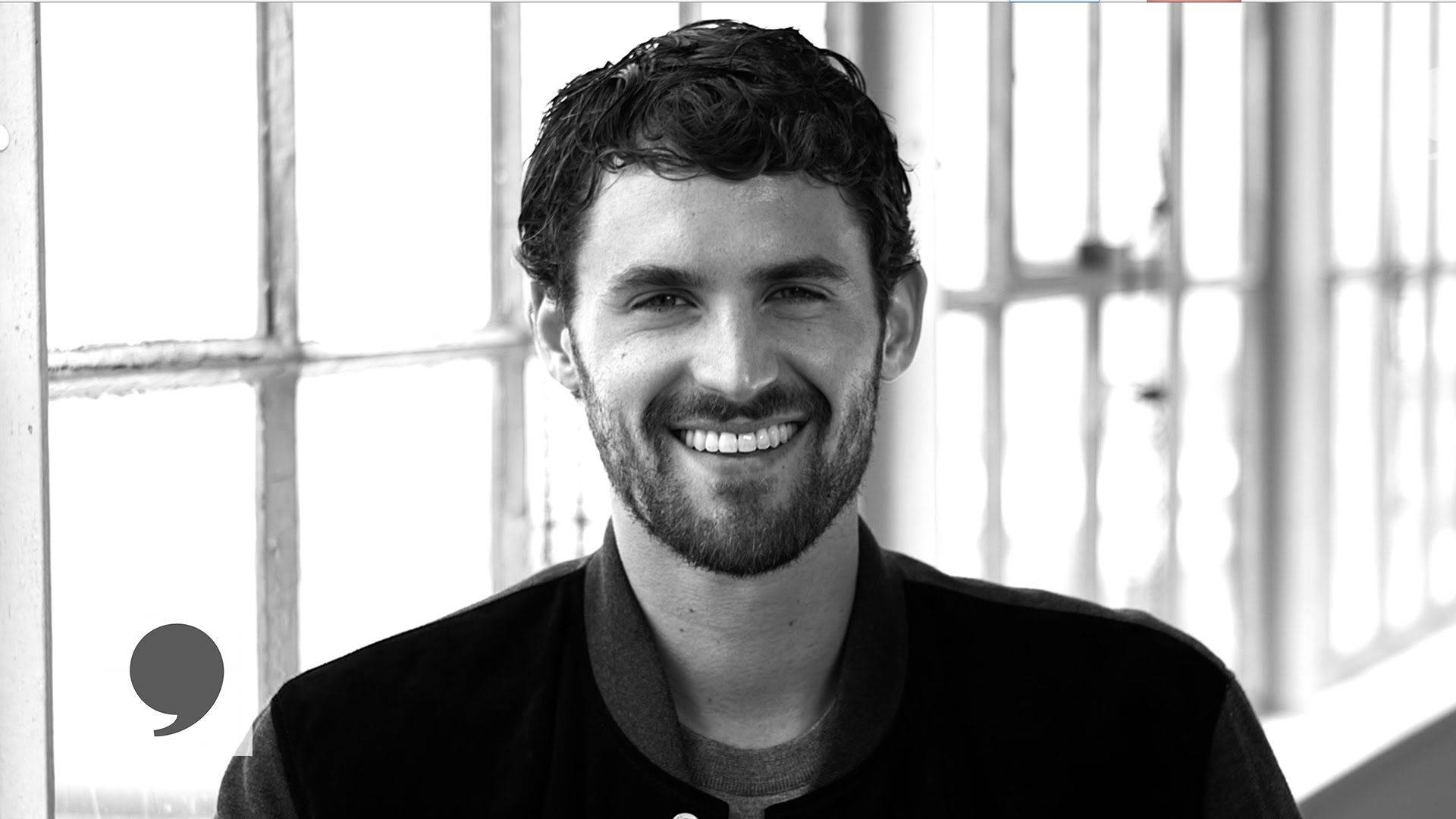 Kevin Love 桌布 壁紙 — 一位留鬍鬚的微笑男子站在明亮的窗前，黑白肖像。