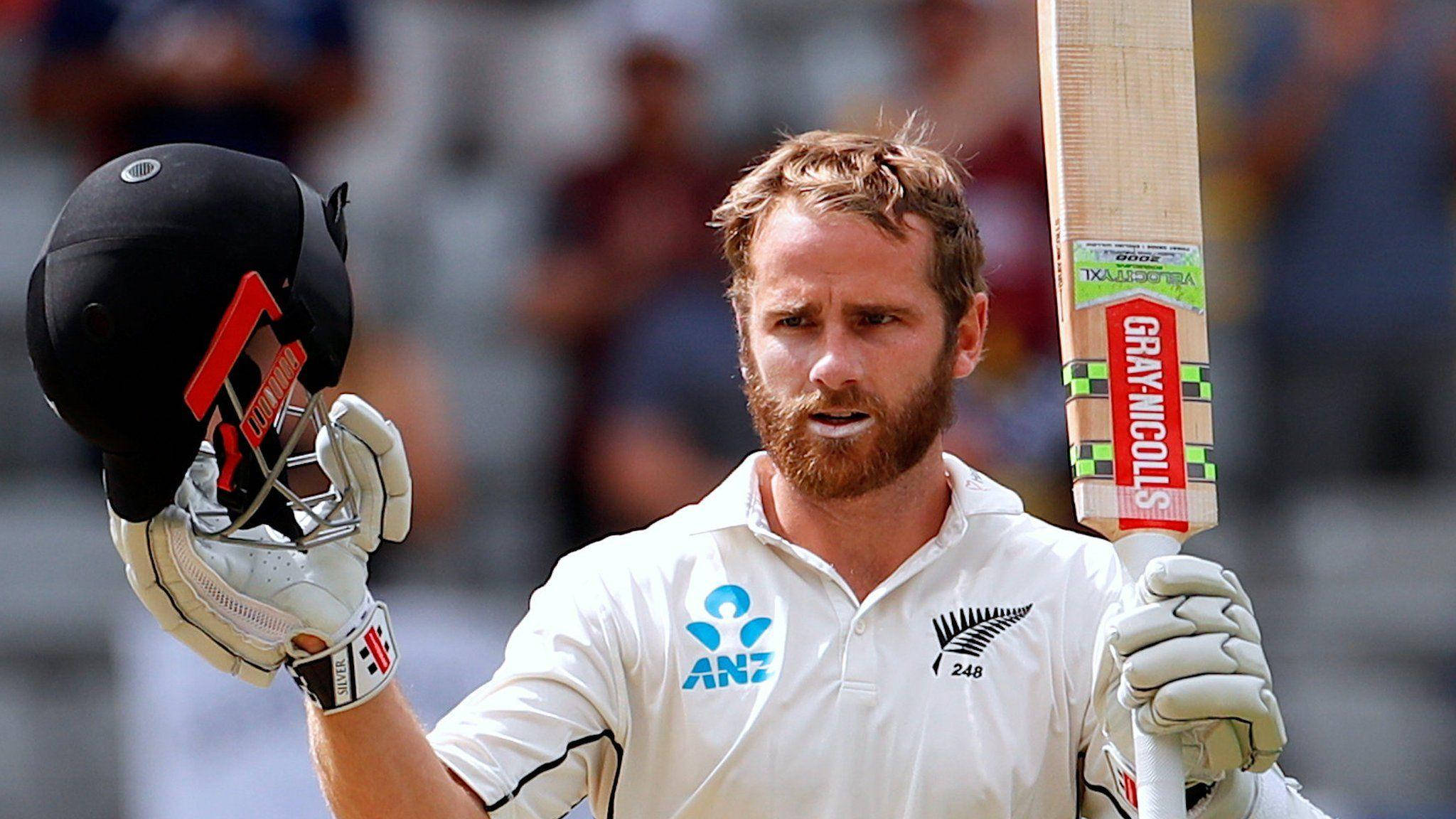 kane williamson 桌布 壁紙 — 一位留鬍鬚的板球運動員身穿白色制服，在日間比賽中專注地拿著頭盔和球棒。