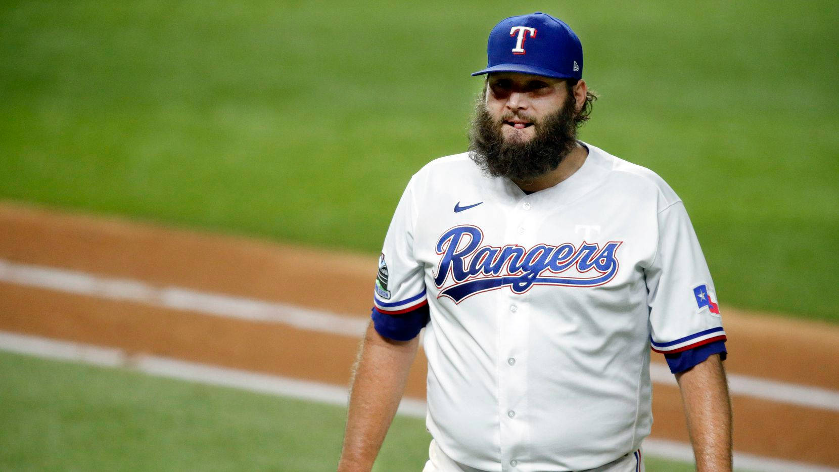 桌布 壁紙 — 一位留鬍鬚的棒球運動員身穿 Rangers 球衣，在綠色球場上行走，場地有棕色泥土和白色線條。