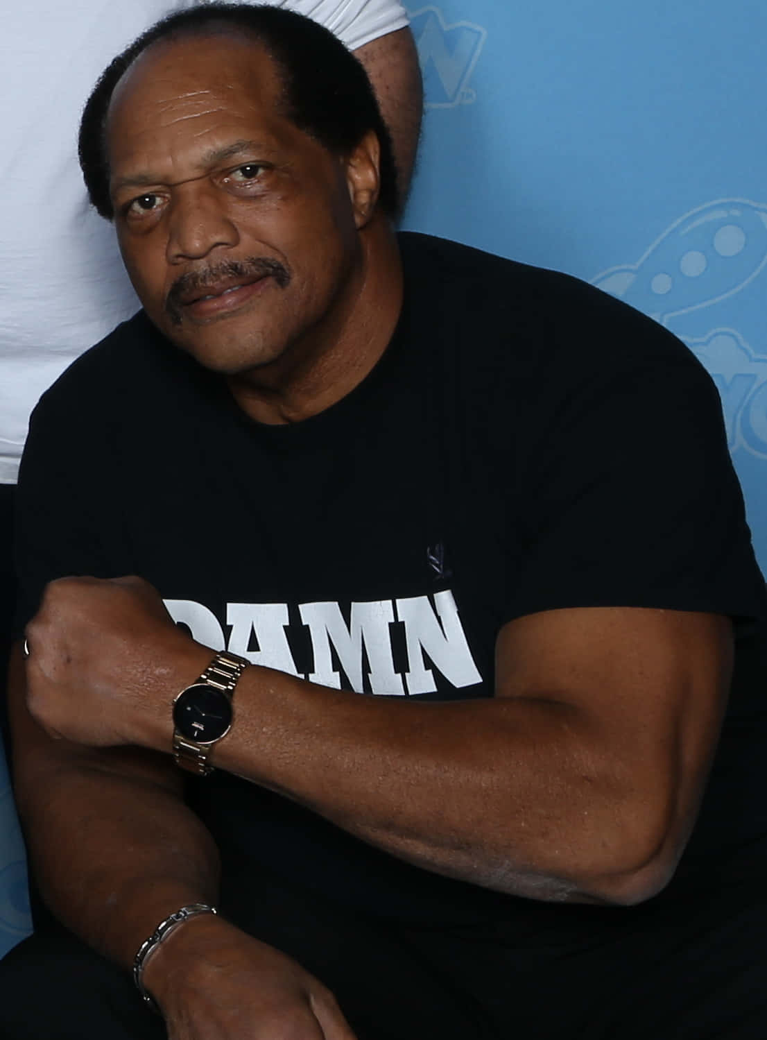 WWE 桌布 壁紙 — 一位留鬍鬚的男人，穿著黑色T恤和金錶，在藍色背景前自信地擺姿勢。