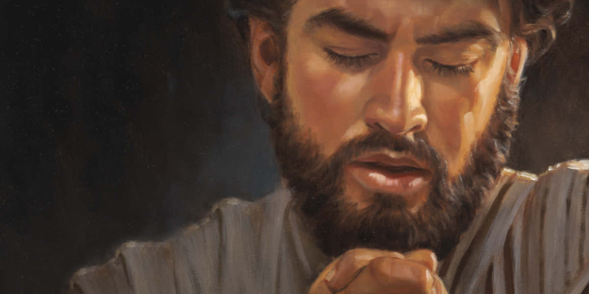 Jesus Praying 桌布 壁紙 — 一位留鬍鬚的男人在昏暗的燈光下閉著眼睛、雙手合十祈禱。