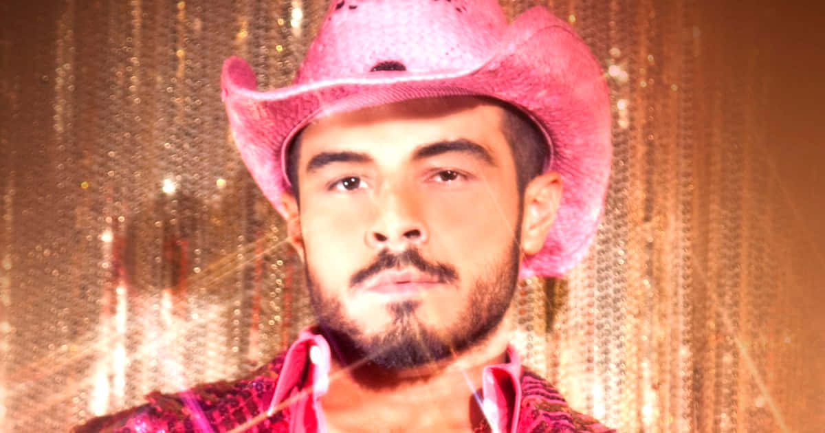 Cowboy 桌布 壁紙 — 一位留鬍鬚的男人戴著粉紅色牛仔帽和亮片襯衫，背景是閃爍的金色窗簾。