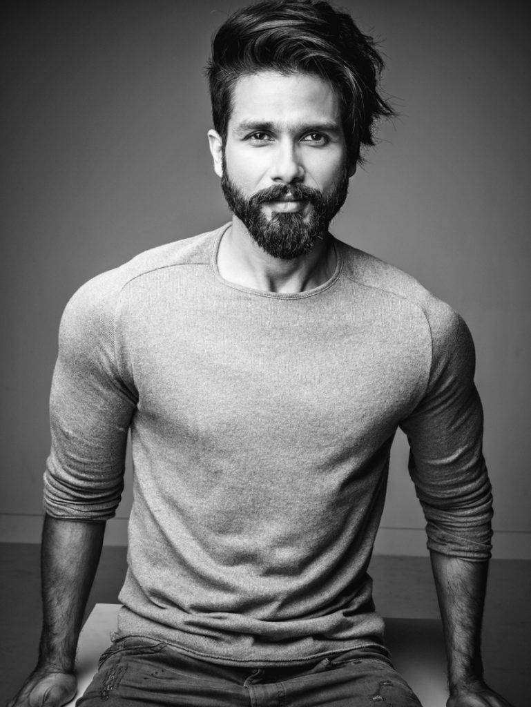Shahid Kapoor 桌布 壁紙 — 一位留鬍鬚的男士，頭髮造型時尚，身穿合身長袖襯衫，自信地坐著的黑白肖像。