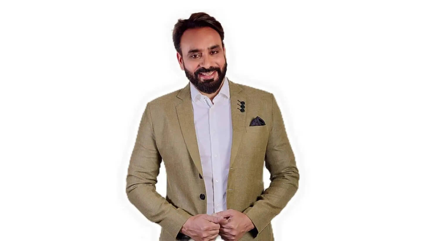 Indian 桌布 壁紙 — 一位留鬍鬚的男士面帶微笑，身穿米色西裝外套內搭白襯衫，背景為純白色。