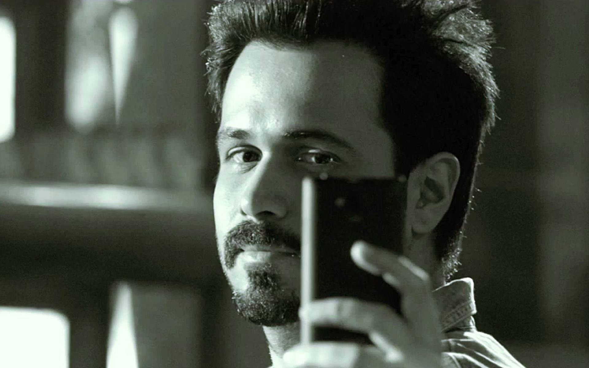 Emraan Hashmi 桌布 壁紙 — 一位留鬍鬚的男子在光線昏暗、帶有柔和陰影和復古風格的房間裡自拍。