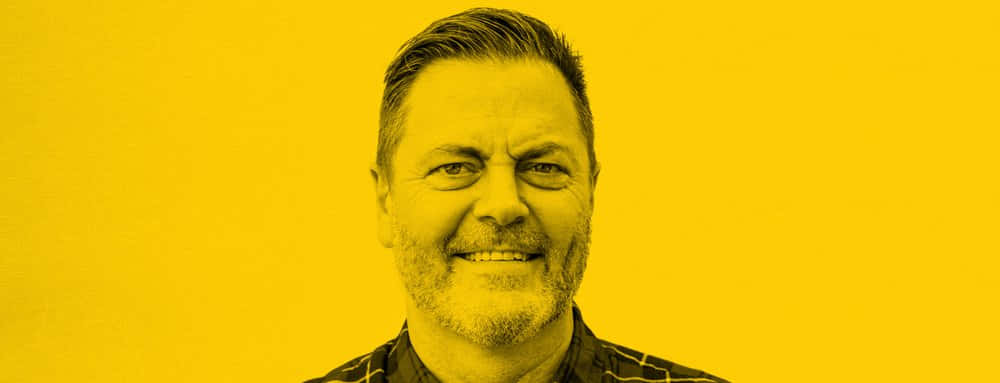 nick offerman 桌布 壁紙 — 一位留鬍鬚的男子在純黃色背景前溫暖地微笑。