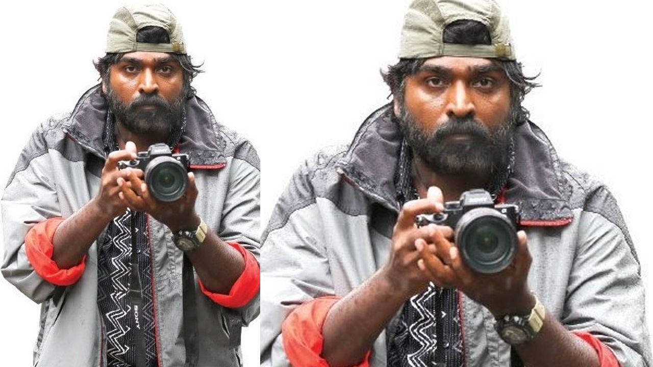 vijay HD 桌布 壁紙 — 一位留鬍鬚的男子戴著帽子和夾克，在純白色背景下專注地拿著相機。