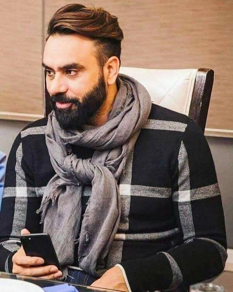 Indian 桌布 壁紙 — 一位留鬍鬚的男子穿著條紋毛衣和灰色圍巾，在室內微笑著拿著電話。